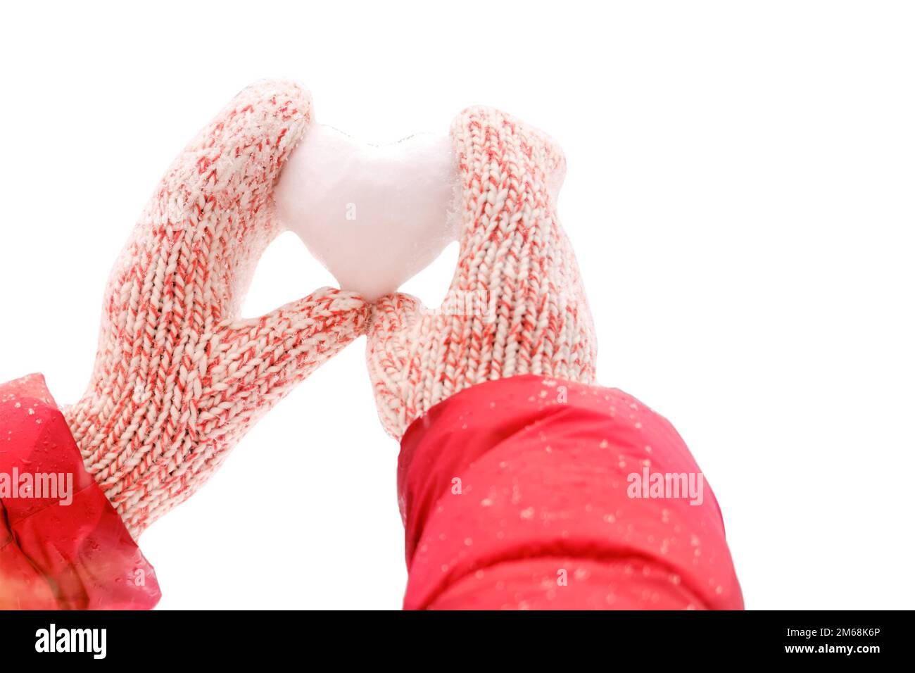 Eine Frau mit weihnachtsmannmütze hält ein Herz aus Schnee vor einem Hintergrund von Waldbäumen, aus nächster Nähe, isoliert auf weißem Hintergrund. Eine Frau, die ein Gehör hält Stockfoto