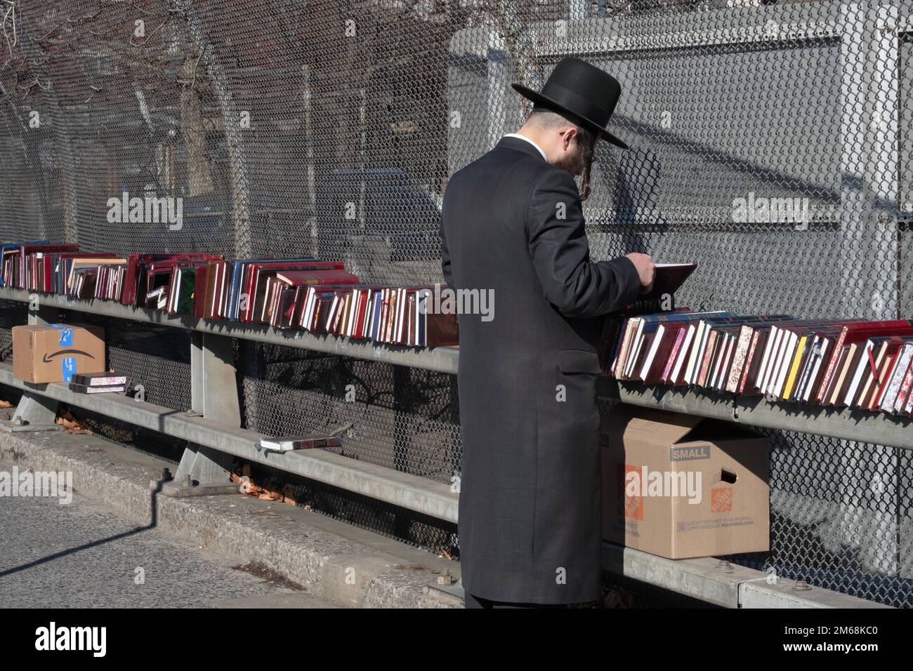 Ein chassidischer jüdischer Mann mit langen Peyus-Geschäften für religiöse Bücher in einem Pop-up-Geschäft in Brooklyn an einem milden Wintertag. Stockfoto