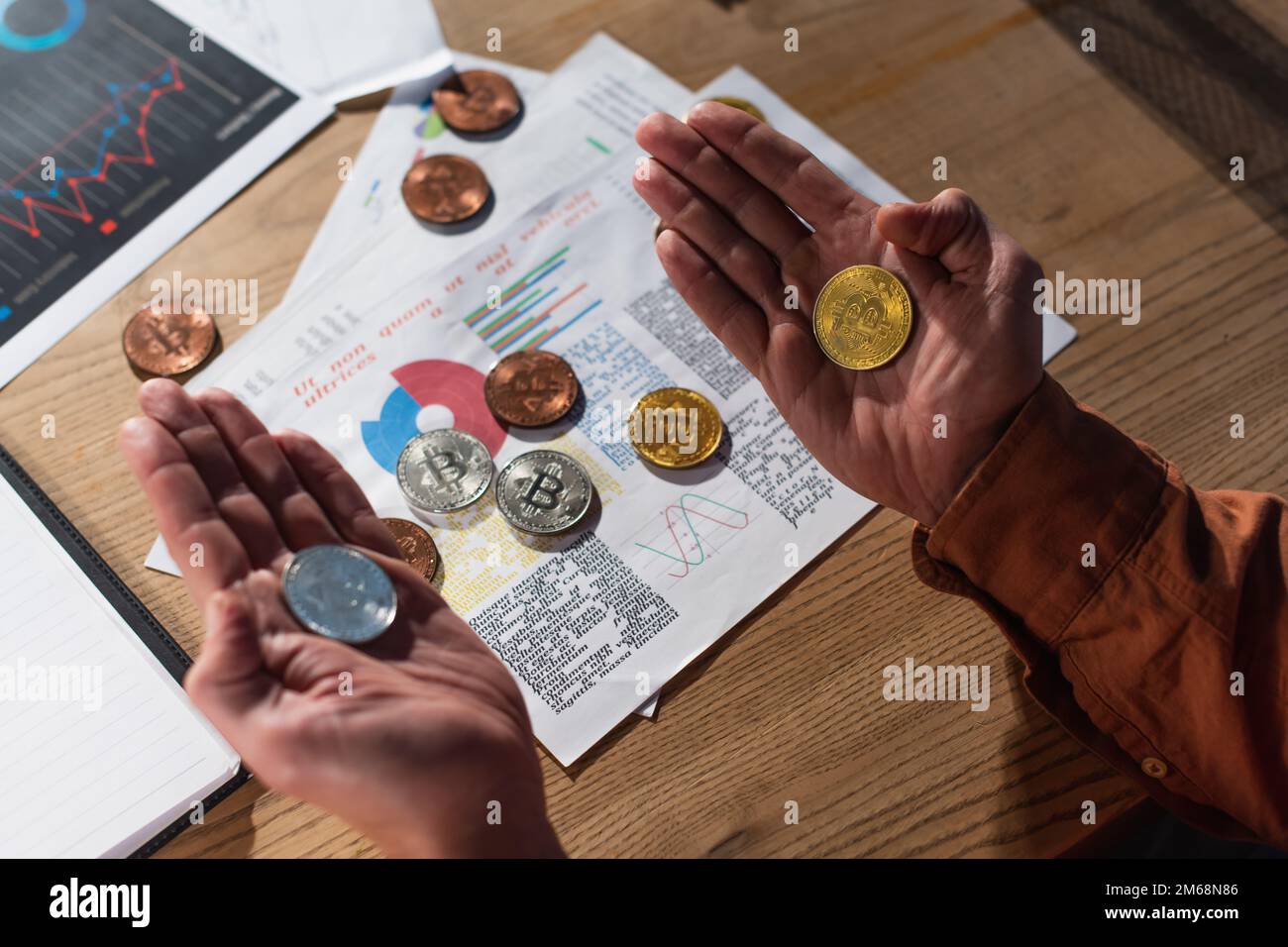 KIEW, UKRAINE - 17. NOVEMBER 2022: Draufsicht eines Geschäftsmanns mit silbernen und goldenen Bitcoins in der Nähe von Papieren mit Karten Stockfoto