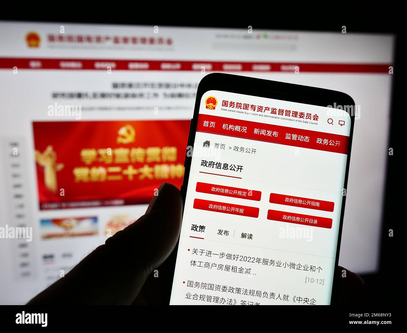 Person, die ein Smartphone hält, mit Webseite und Logo der staatseigenen chinesischen sonderkommission SASAC auf dem Bildschirm. Konzentrieren Sie sich auf die Mitte des Telefondisplays. Stockfoto