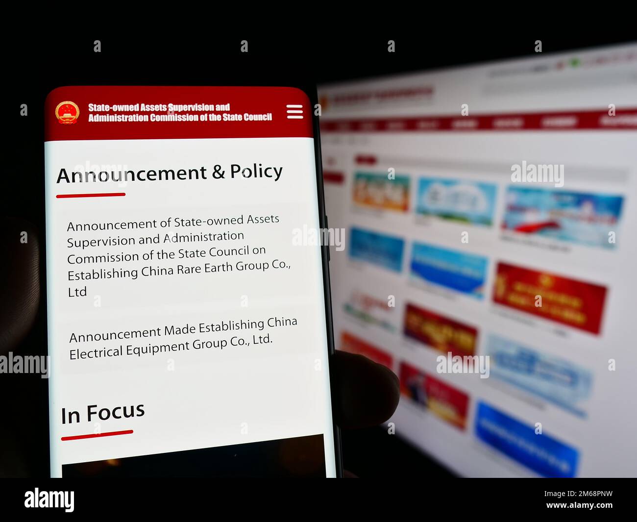 Person, die ein Smartphone hält, mit Website und Logo der staatseigenen chinesischen sonderkommission SASAC auf dem Bildschirm. Konzentrieren Sie sich auf die Mitte des Telefondisplays. Stockfoto