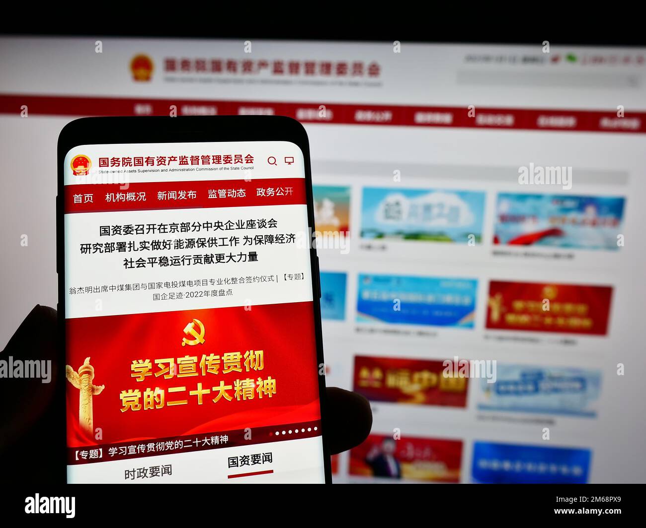 Person, die ein Mobiltelefon hält, mit Webseite und Logo der staatseigenen chinesischen sonderkommission SASAC auf dem Bildschirm. Konzentrieren Sie sich auf die Mitte des Telefondisplays. Stockfoto