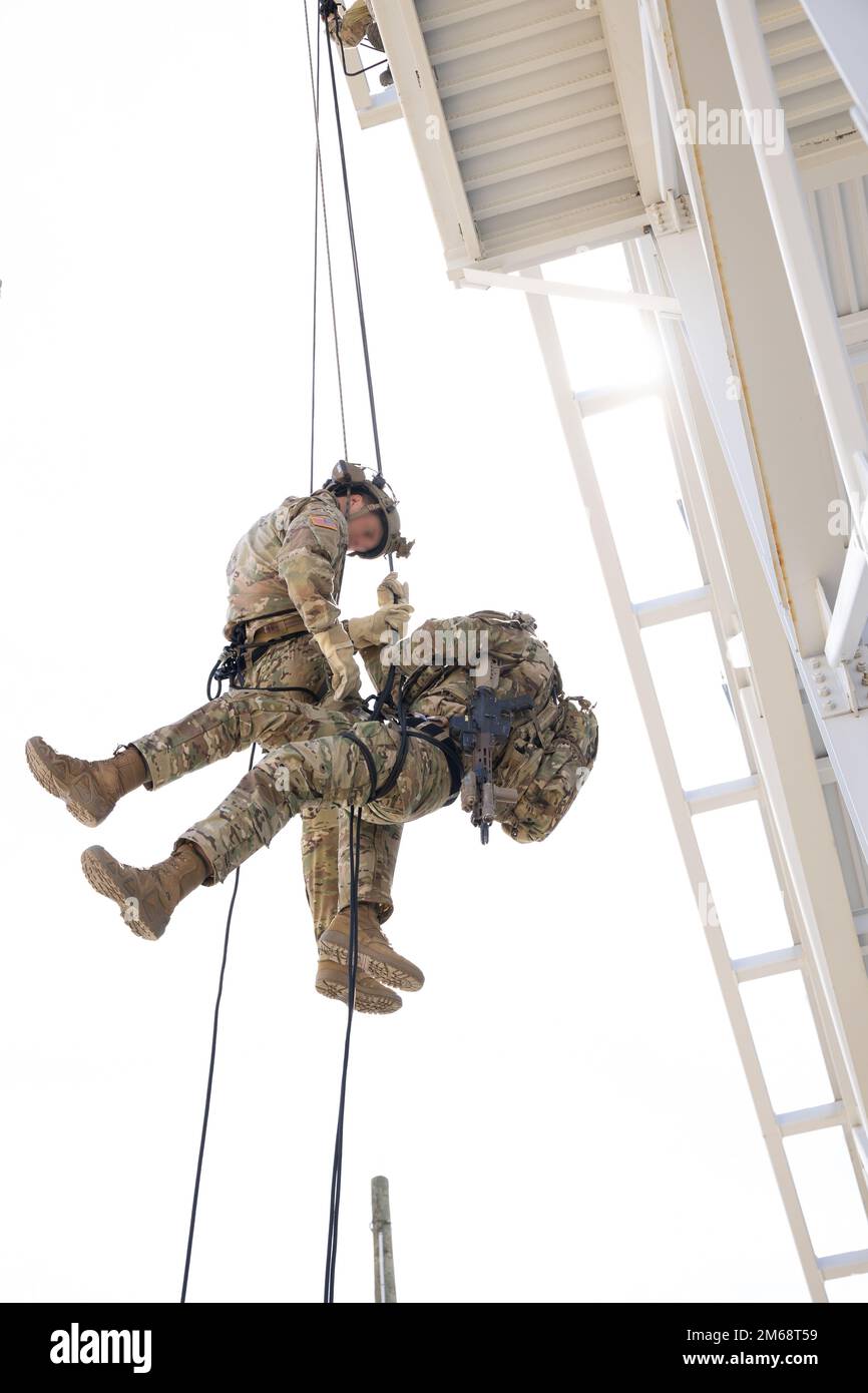 Ein Green Beret mit 10. Special Forces Group (Airborne) hilft bei der Wiederherstellung einer simulierten Hängevorrichtung von einem Turm in Fort Carson, Colorado, am 19. April 2022. Spezialkräfte verwenden Abseilen, um aus erhöhten Positionen in Bereiche einzuhängen, wenn die Mission Zeit oder Überraschung erfordert. Stockfoto
