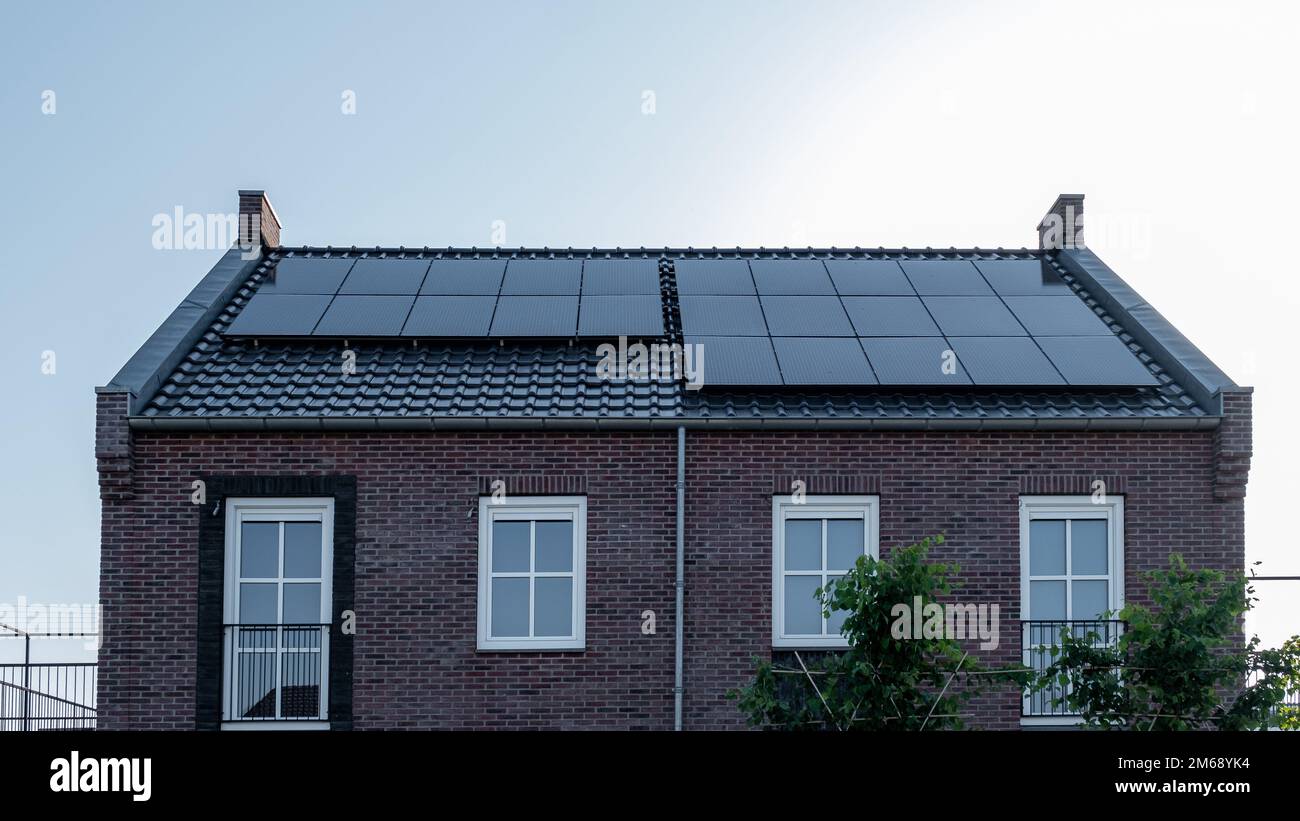 Neu errichtete Häuser mit Sonnenkollektoren auf dem Dach vor einem sonnigen Himmel, erneuerbare Energie grüne Energie Stockfoto