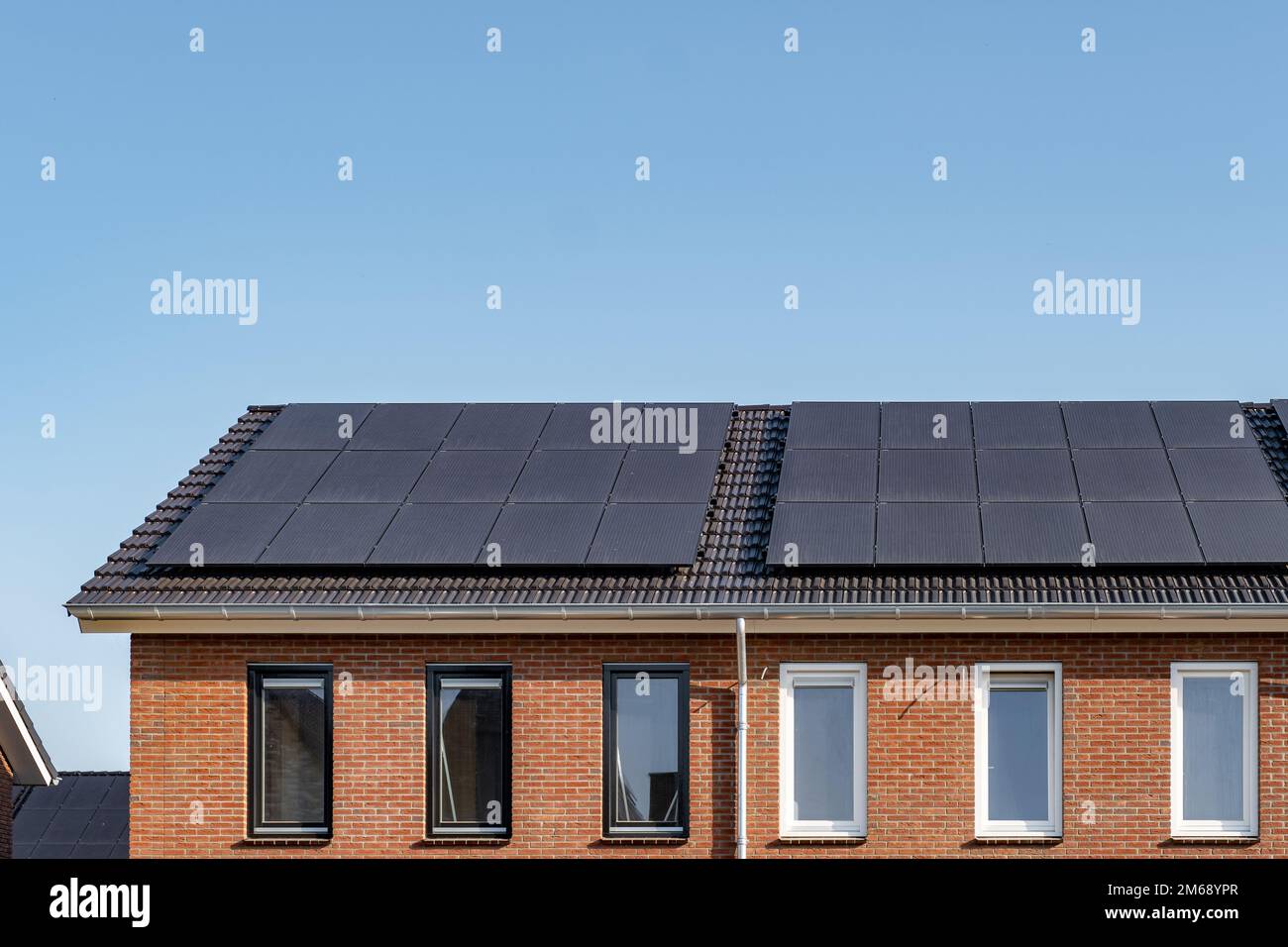Neu errichtete Häuser mit Sonnenkollektoren auf dem Dach vor einem sonnigen Himmel, erneuerbare Energie grüne Energie Stockfoto