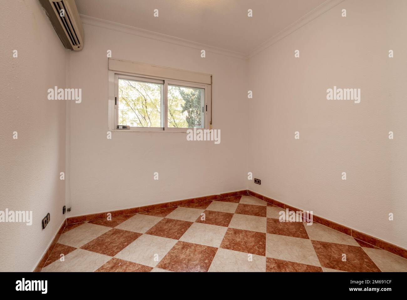 Leeres Zimmer mit karierten Steinzeug-Böden, doppelwandigen Aluminiumfenstern und Klimaanlage Stockfoto
