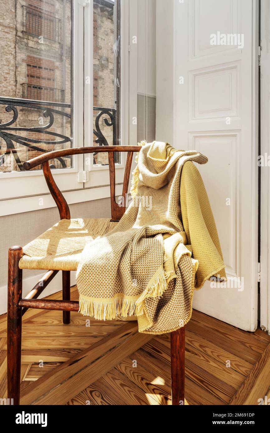 Holzsessel mit Decken in einer Ecke mit Fenster mit weißen Holzläden Stockfoto
