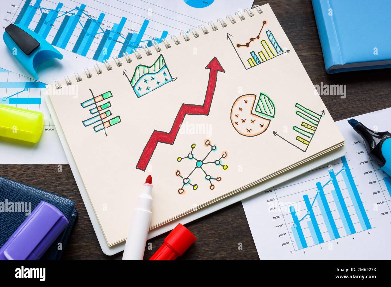 Notizblock mit Geschäftsdiagrammen und Finanzdiagrammen und wachsendem Pfeil als Symbol für Erfolg. Stockfoto