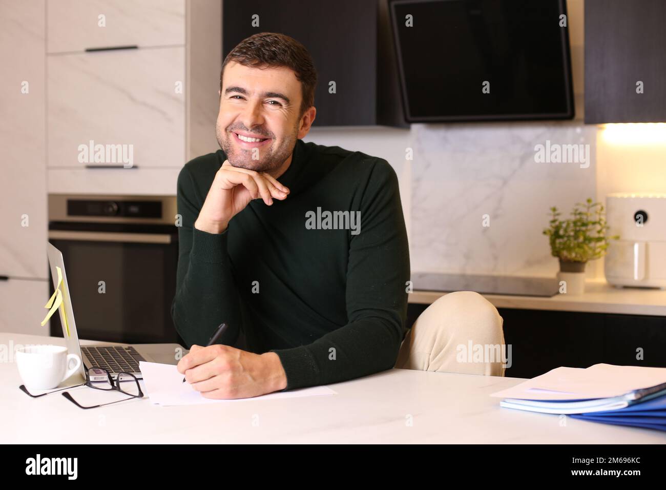 Ein Mann, der mit Stift und Papier im Home Office schreibt Stockfoto