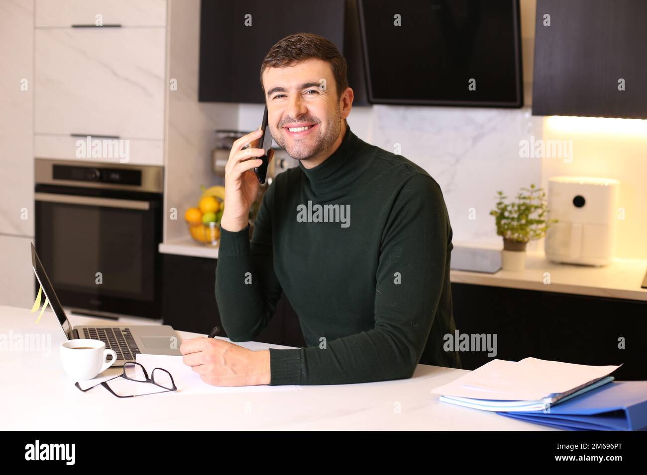 Ein gutaussehender Mann, der vom Heimbüro aus telefoniert Stockfoto