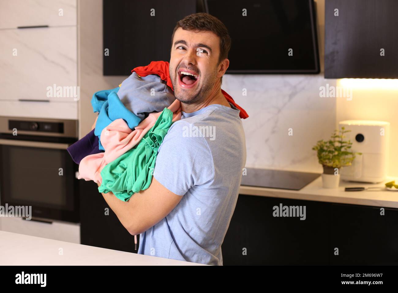 Gestresster Mann, der einen Haufen schmutzige Sachen in der Hand hat Stockfoto