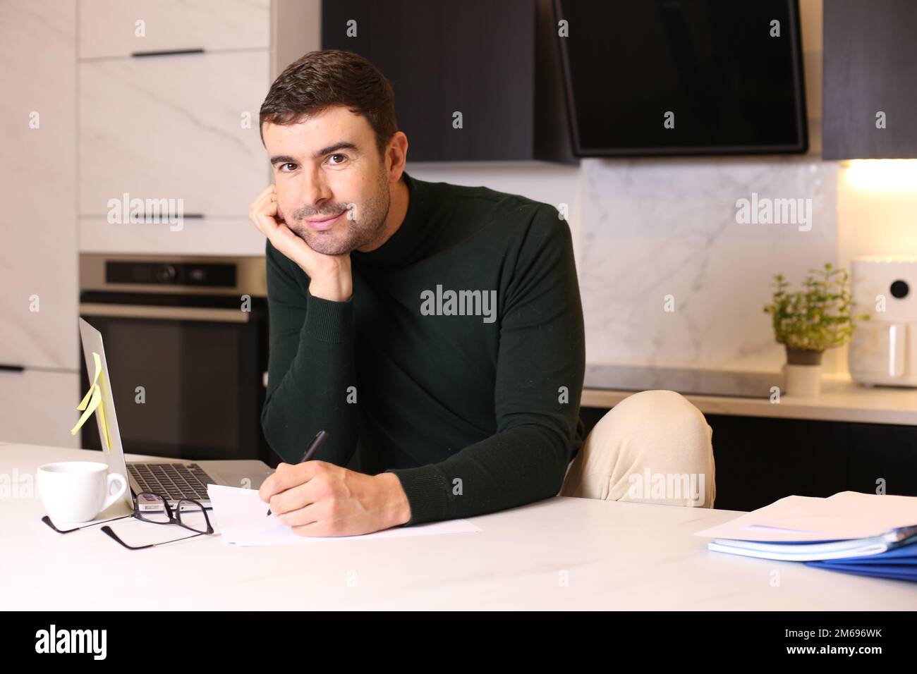 Ein Mann, der mit Stift und Papier im Home Office schreibt Stockfoto