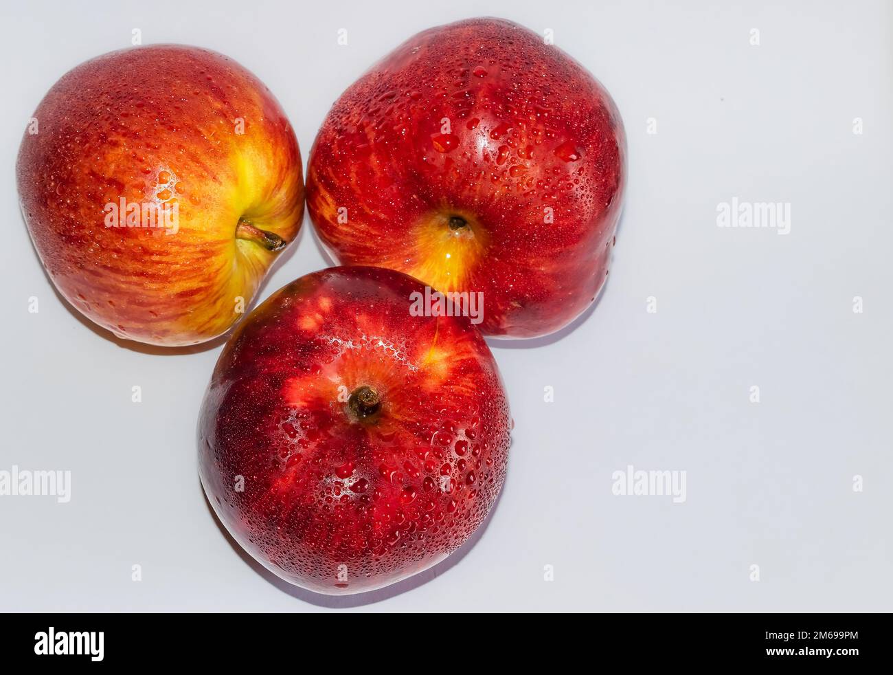 Wunderschöne Nahaufnahme von rotem Apfel auf weißem Hintergrund mit verschwommenem Hintergrund. Roter Apfel mit Wassertropfen auf weißem Hintergrund. Stockfoto