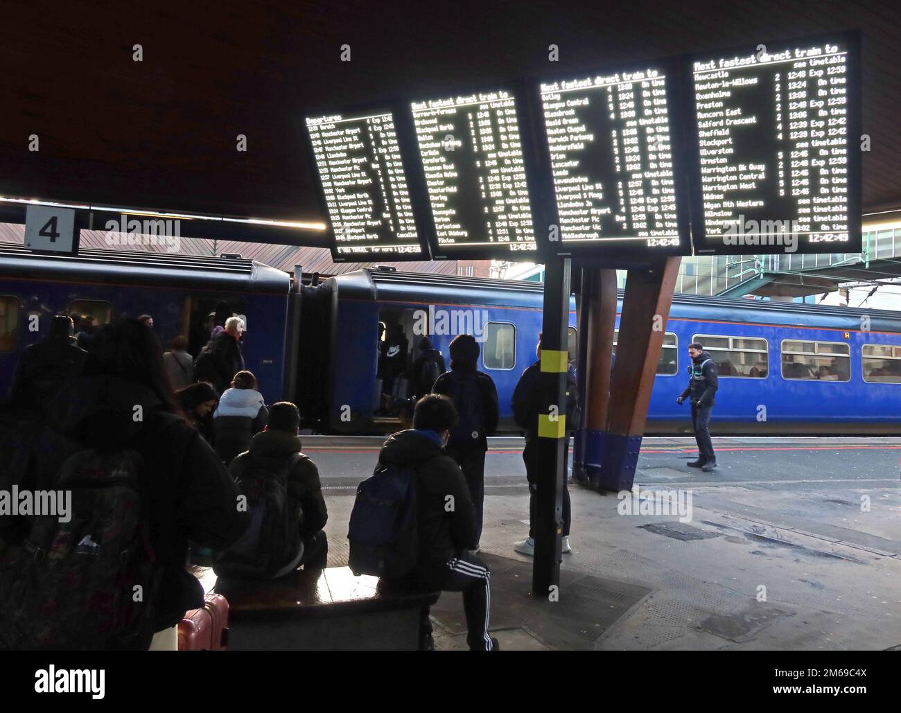 Informationstafeln am Bahnhof Oxford Road, Manchester, England, Großbritannien, M1 6FU, Bahnsteig 4 mit wartenden Pendlern Stockfoto