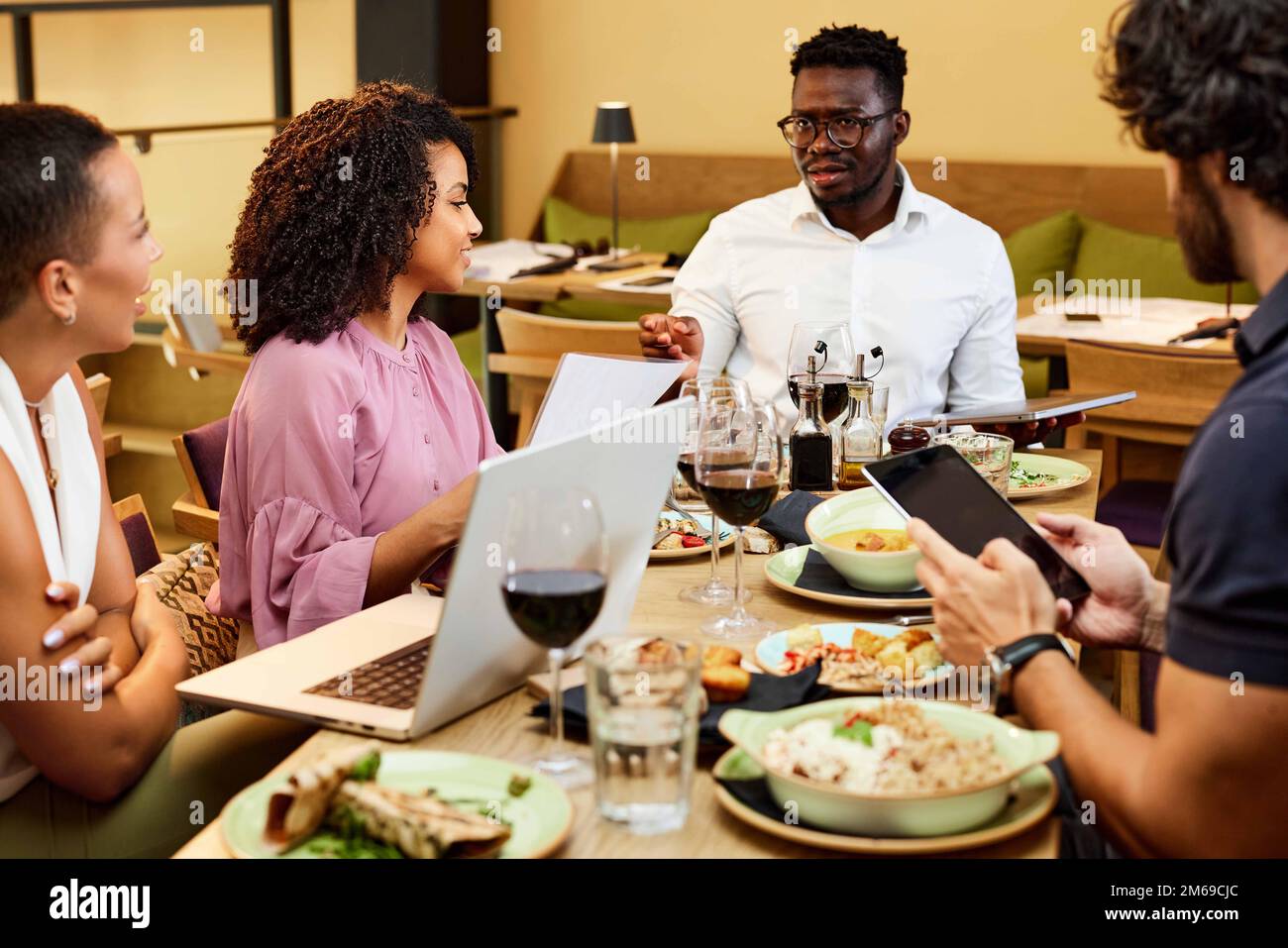 Geschäftsleute aus verschiedenen Rassen veranstalten ein Geschäftsessen und diskutieren das Projekt in einem Restaurant. Stockfoto