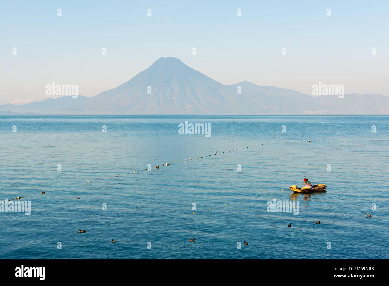 Einheimischer Maya-Fischer auf dem Atitlan-See bei Panajachel mit Vulkan im Hintergrund, Guatemala. Stockfoto