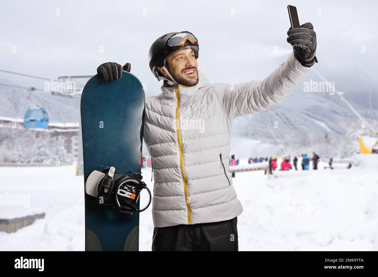 Ein Typ mit einem Snowboard macht ein Selfie mit einem Smartphone in einem Skigebiet Stockfoto