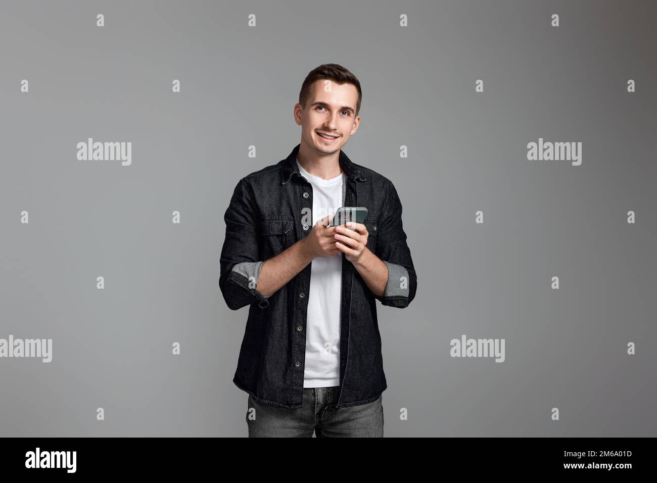 Mann mit Handy isoliert auf grauem Hintergrund. Stockfoto