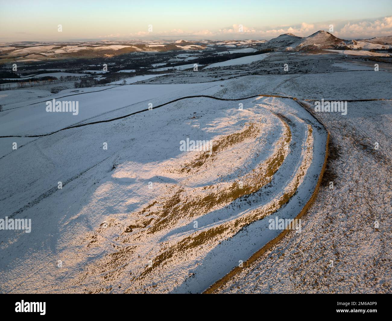 Luftaufnahme von Cauldhiels Hillfort mit Details von Schnee und niedriger Wintersonne mit den Eildons im Hintergrund. Stockfoto
