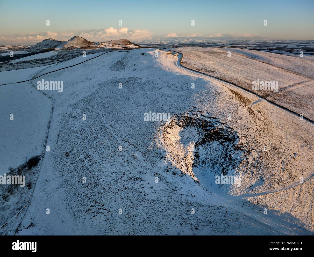 Luftaufnahme von Cauldhiels Hillfort mit Details von Schnee und niedriger Wintersonne mit den Eildons im Hintergrund. Stockfoto