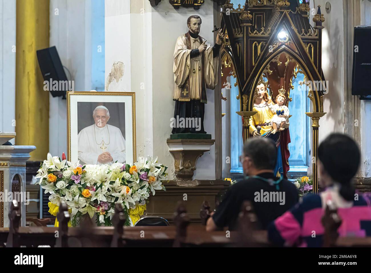 Katholische Anhänger beten vor dem Foto des verstorbenen Papstes in der Rosenkirche während der Hommage an den Tod des Papstes Emeritus Benedikt XVI Der verstorbene Papst Emeritus Benedikt XVI. Starb am 31. Dezember 2022 im Alter von 95 Jahren im Kloster Hook Ecclesiae im Vatikan. Stockfoto