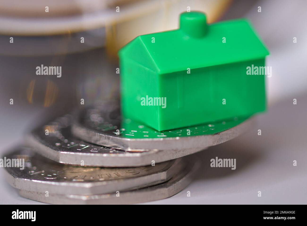 Ein grünes Haus auf einem Haufen 50-Pence-Münzen, Wohnungsmarkt, Stabilität, Immobilienpreise, Hypotheken Stockfoto
