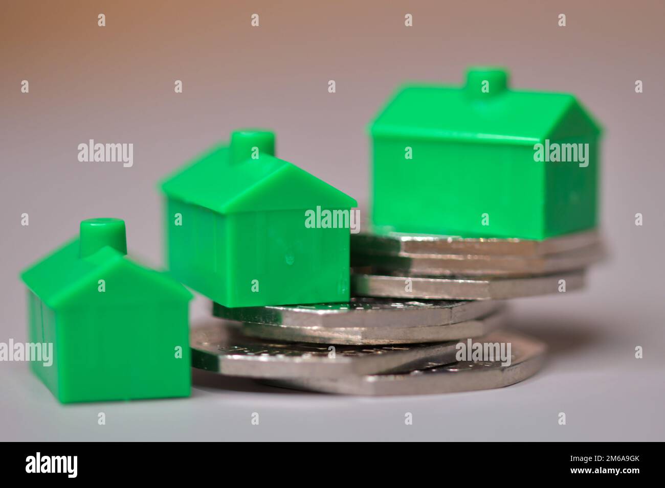 Drei Grünhäuser auf einem Haufen von 50 Pence-Stücken, Stabilität des Immobilienmarktes, Immobilienpreise, Hypotheken Stockfoto