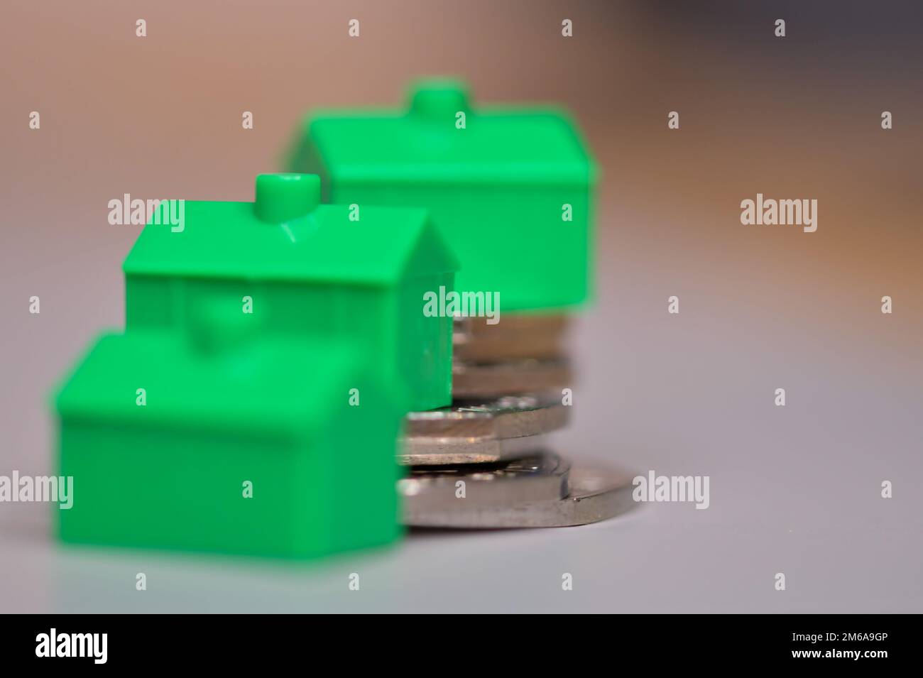Drei Grünhäuser auf einem Haufen von 50 Pence-Stücken, Stabilität des Immobilienmarktes, Immobilienpreise, Hypotheken Stockfoto