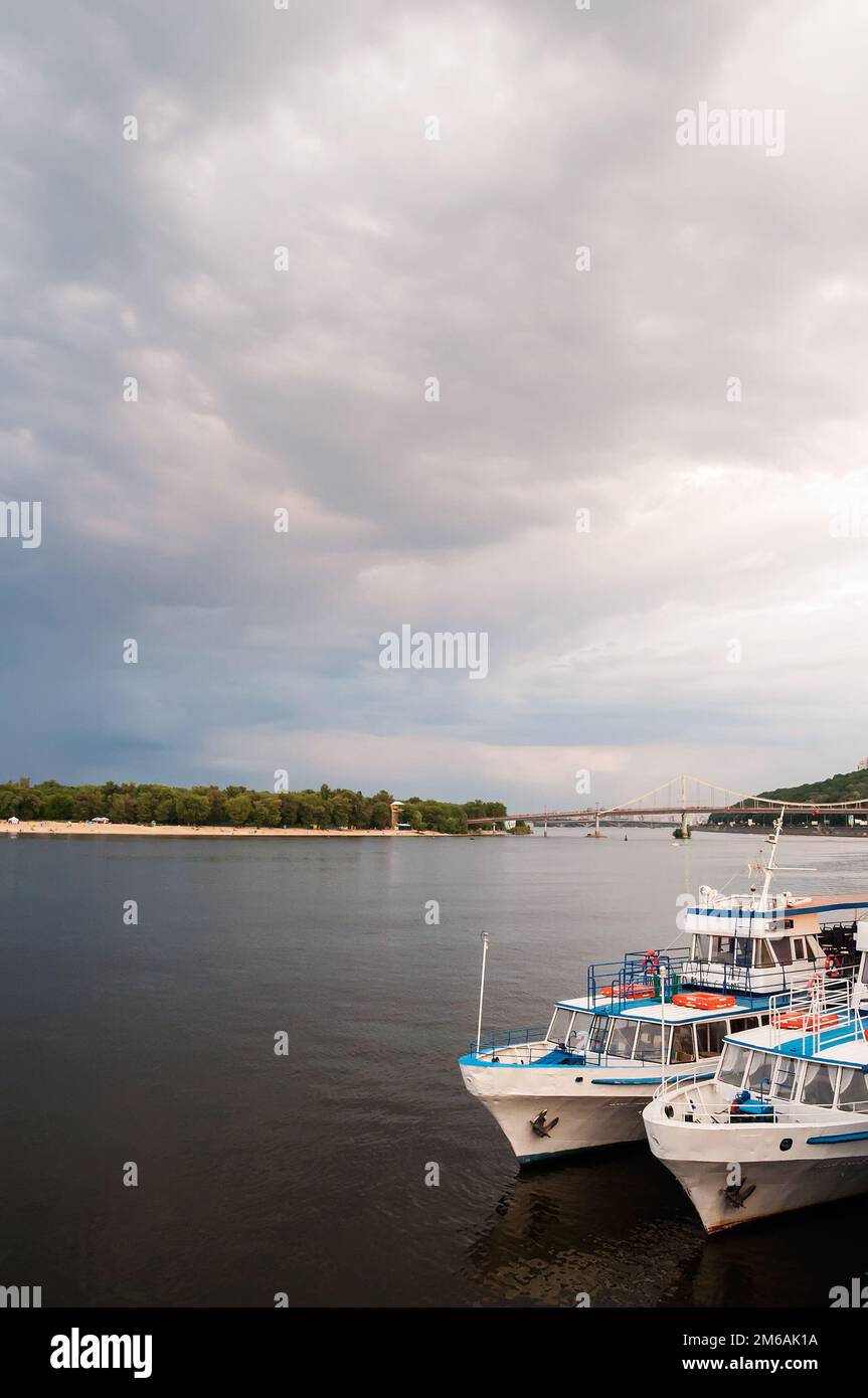 Kiew, Ukraine. Juli 19. 2014. Blick auf den Dnieper River mit Vergnügungsbooten, Stadtstrand und Fußgängerbrücke im Hintergrund. Bewölktes Wetter mit d Stockfoto