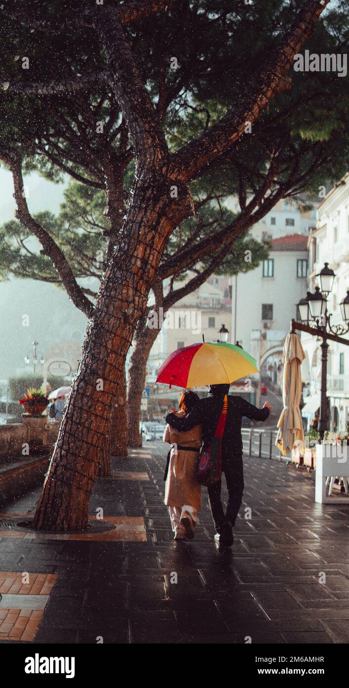 Ein Paar unter einem Schirm, das an der amalfiküste spaziert Stockfoto