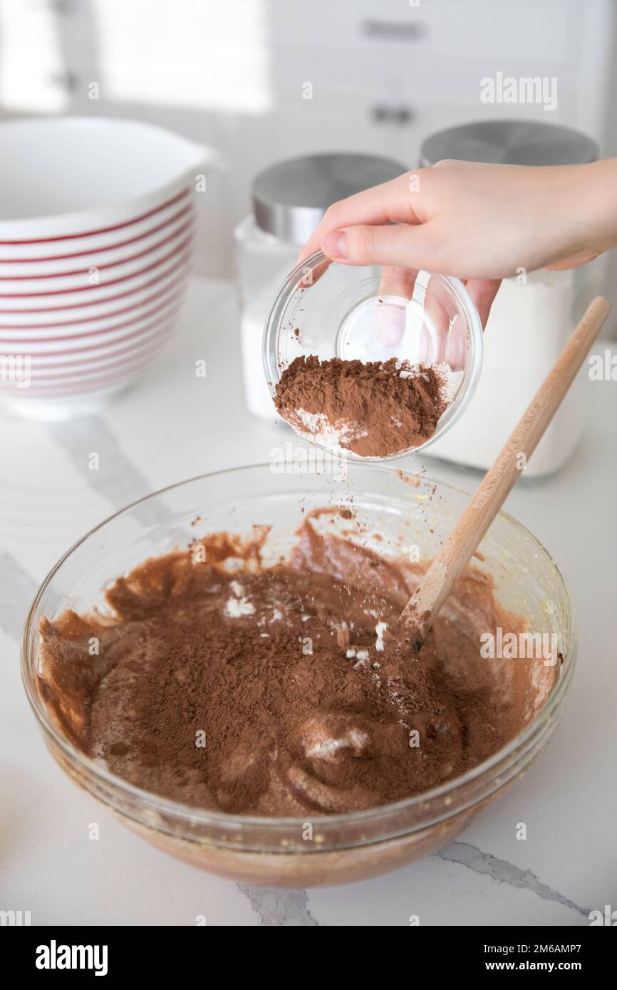 Das Kakaopulver wird in die Mischschüssel gesiebt, um Schokoladenzuckercreme herzustellen Stockfoto