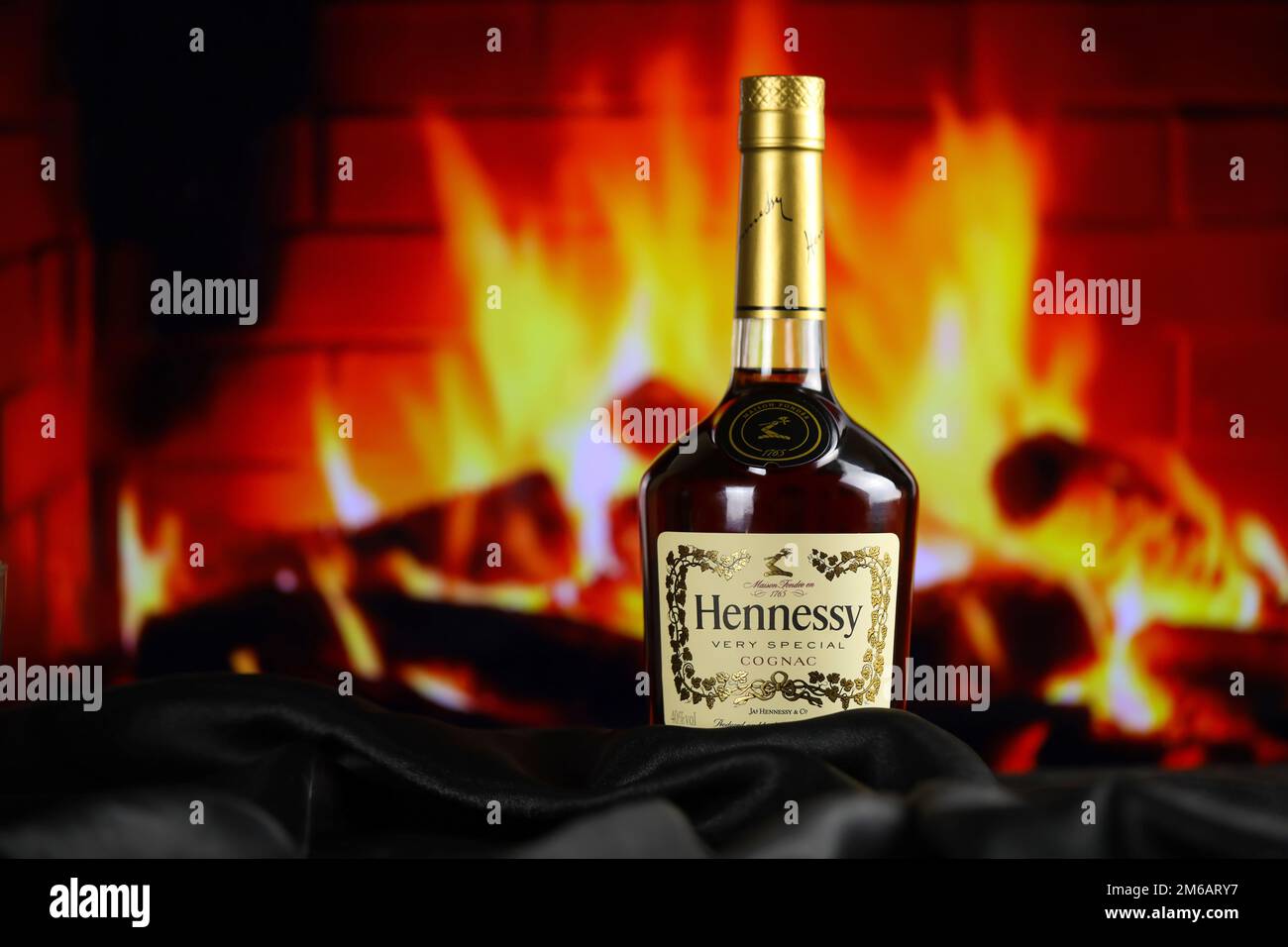 KIEW, UKRAINE - 4. MAI 2022 Hennessy Very Special Original Alkoholflasche auf Holztisch mit rotem Kamin im Hintergrund. Elite-Alkoholproduktion Stockfoto