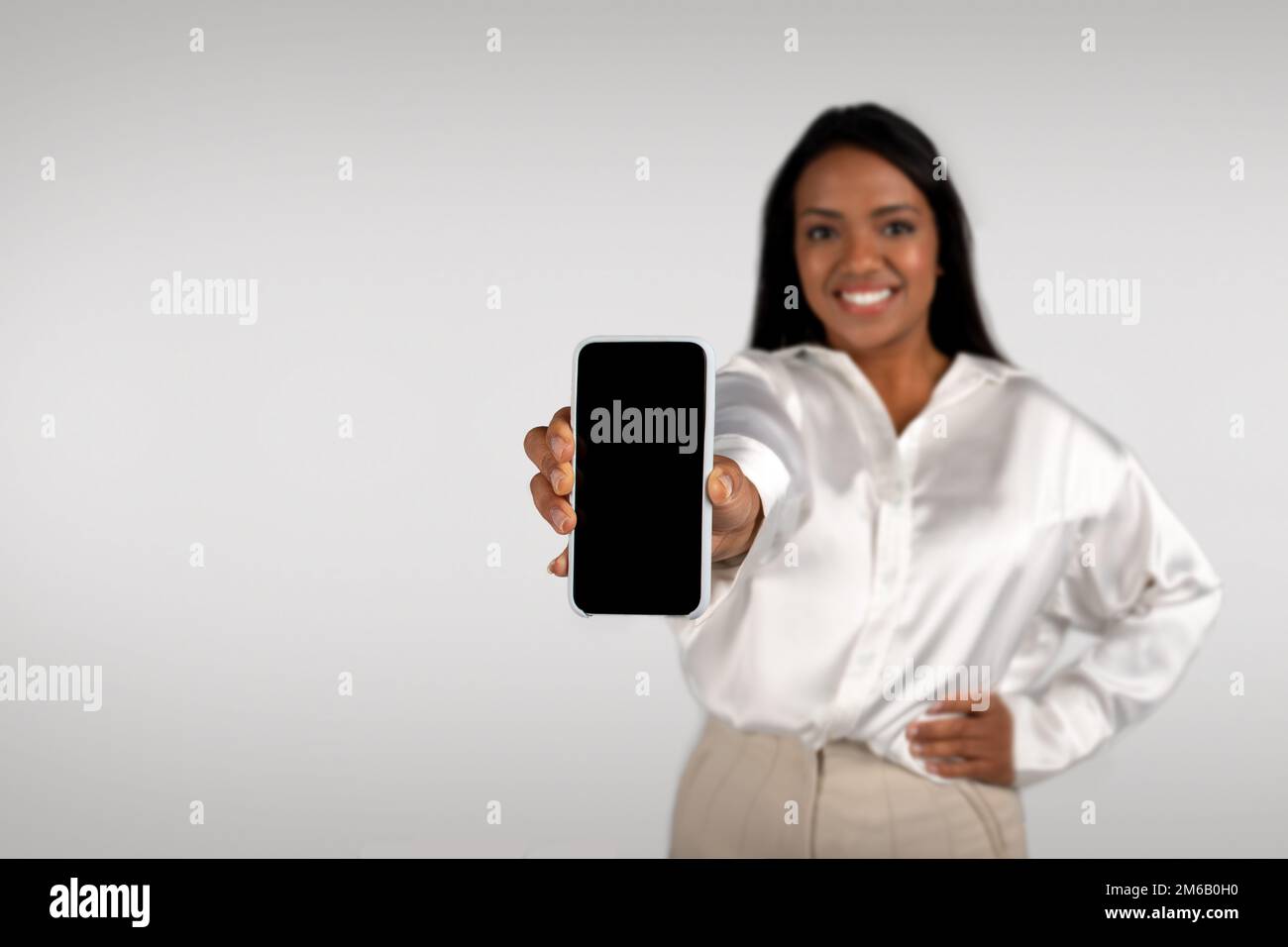 Fröhliche junge afroamerikanische Geschäftsfrau Show-Smartphone mit leerem Bildschirm Stockfoto