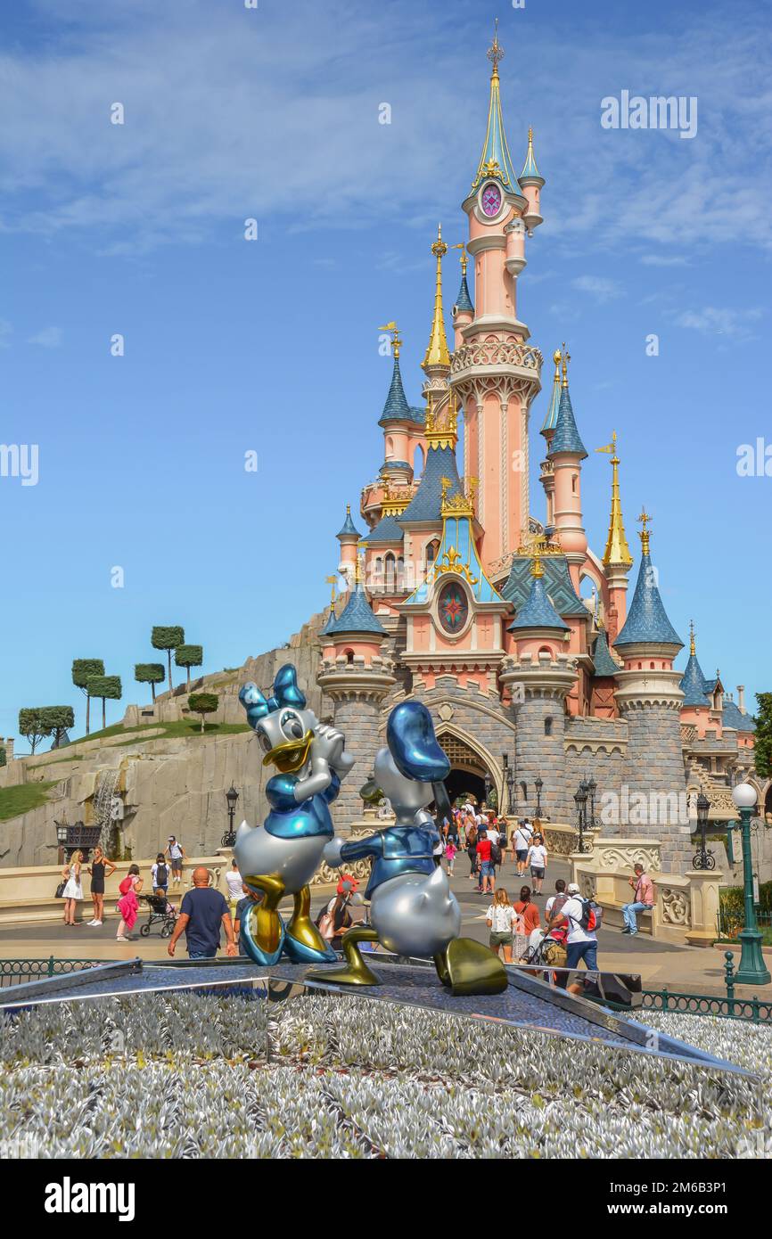 Ein vertikaler Blick auf Disneyland mit einem Märchenschloss hinter der Statue von Donald Duck und Gänseblümchen in Paris, Frankreich Stockfoto