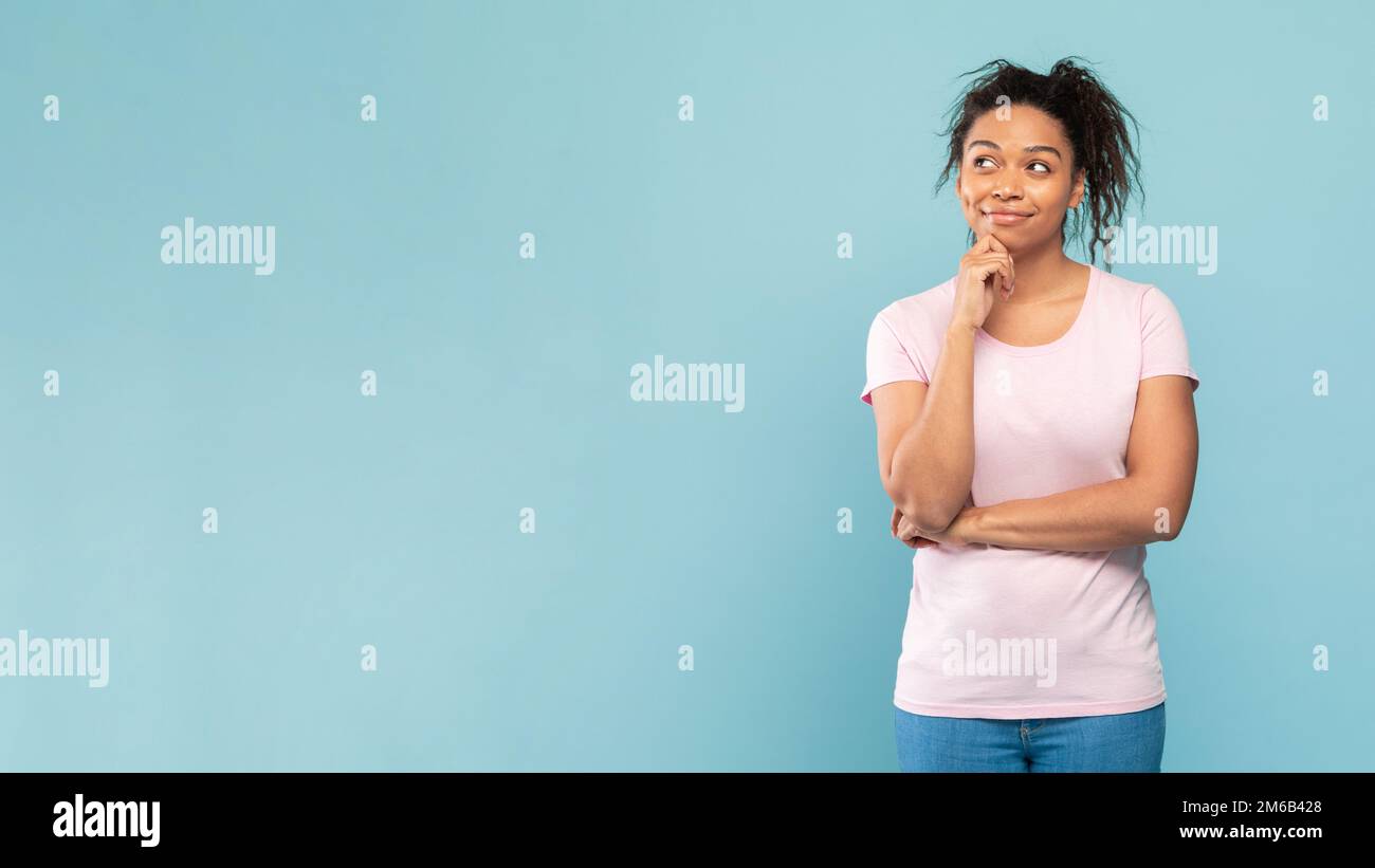 Eine fürsorgliche afroamerikanische Frau, die auf freien Raum blickt und sich auf blauem Studiohintergrund posiert Stockfoto
