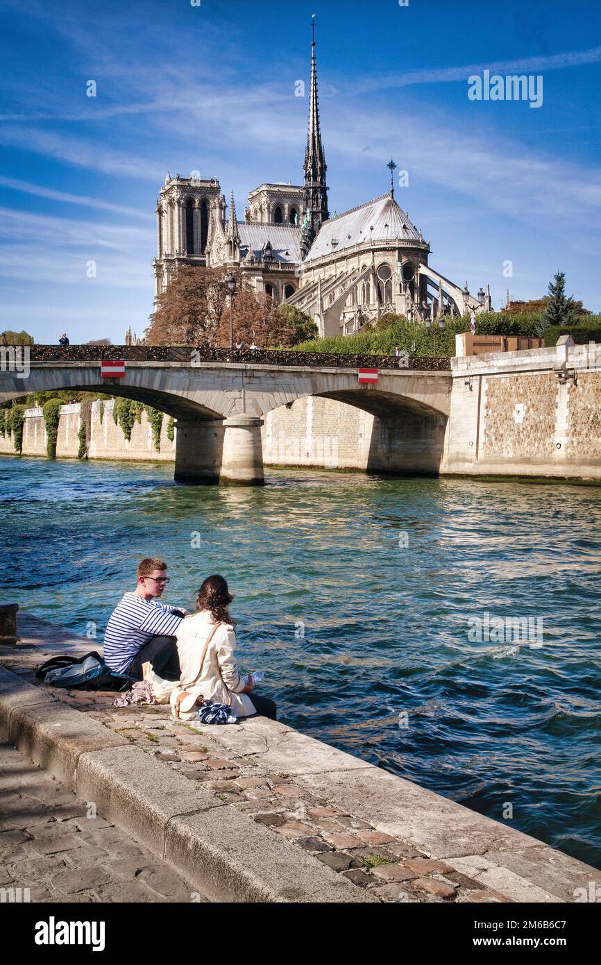 Ein paar genießt das ideale Wetter entlang der Seine unterhalb der Pont Archeveche und Notre Dame.  Paris, Frankreich. Stockfoto