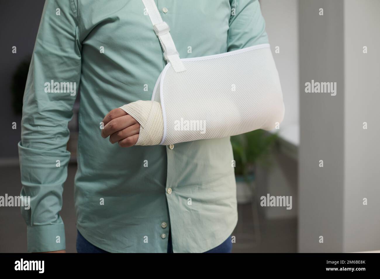Ein Mann trägt einen Verband und eine Schlinge nach der Operation am Arm mit einer Gelenkluxation Stockfoto