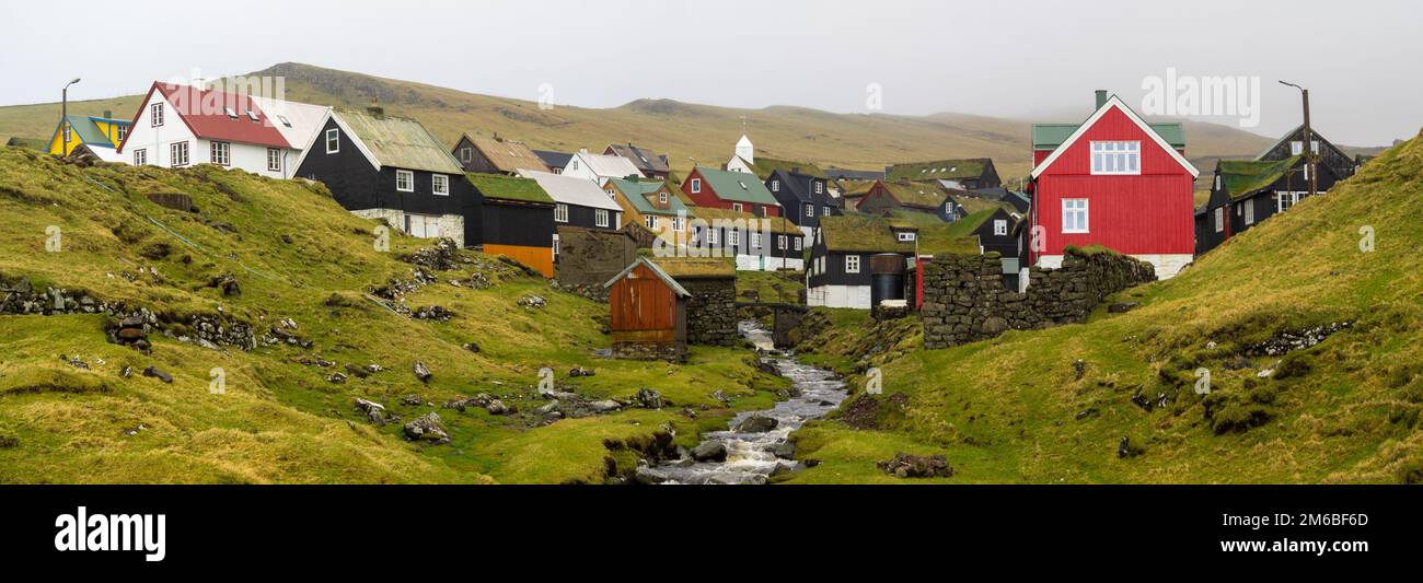 Der Bach, der an Häusern mit tuf-Dächern in Mykines vorbeiführt Stockfoto