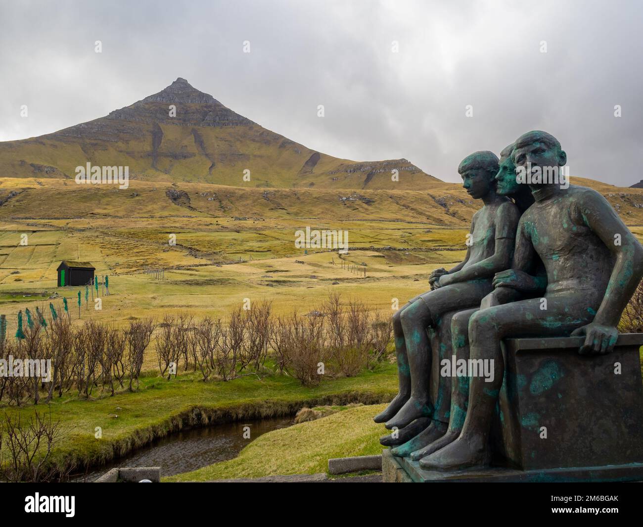 Gjógv Fritjof Joensen Skulptur einer Mutter und zweier Kinder mit dem Berg Middagsfjall im Hintergrund Stockfoto