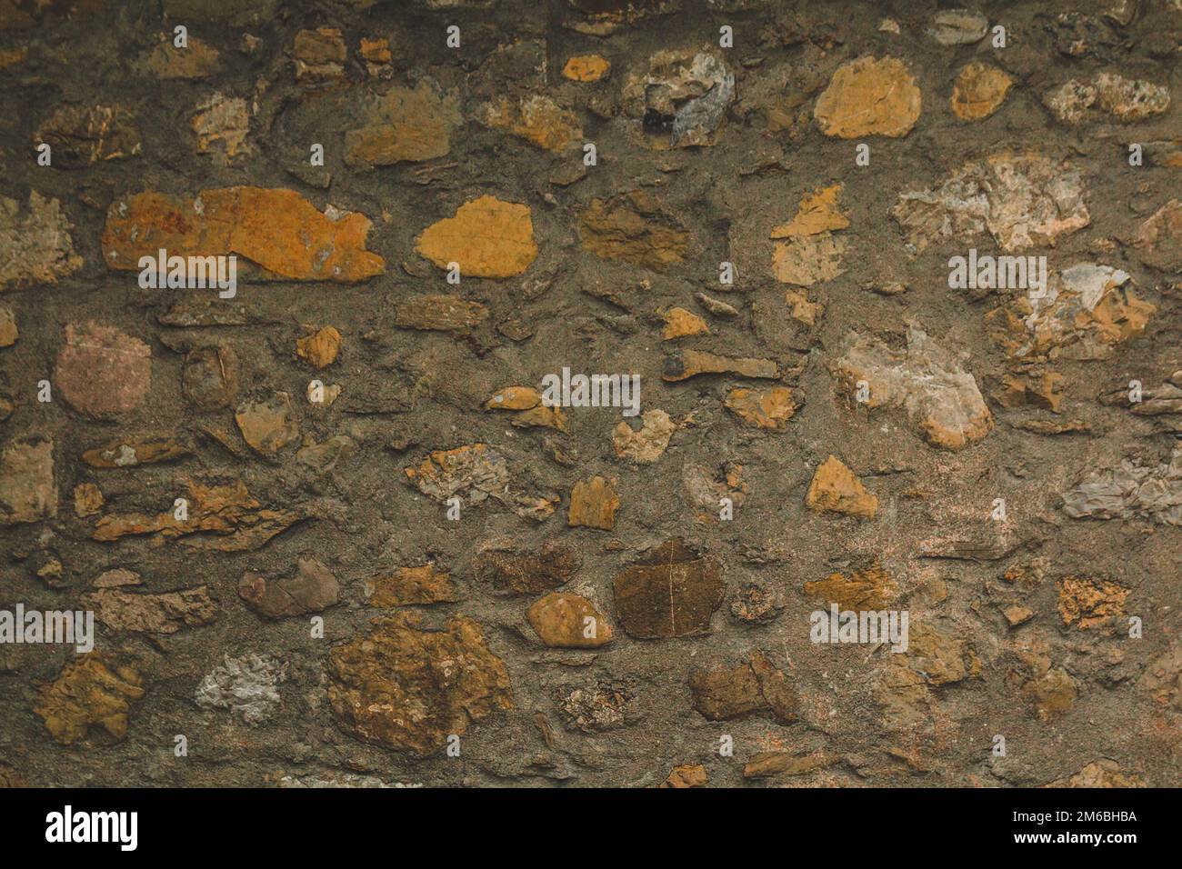 Horizontale Steinsteinpflasterwand mit Mörtel für einen strukturierten Hintergrund Abstraktes Material, das leicht schmutzig und uneinheitlich ist Stockfoto