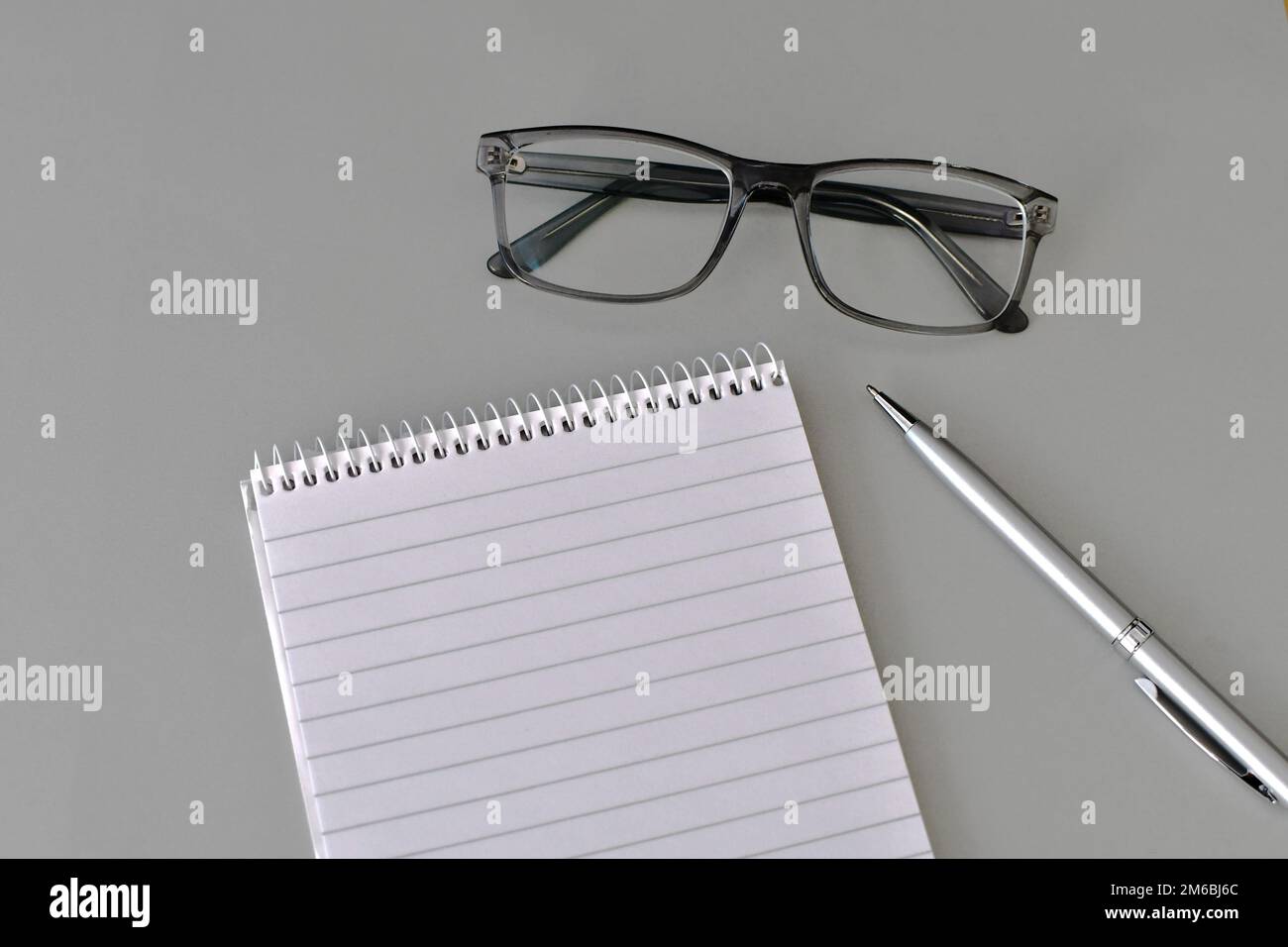 Flaches Display mit Notizblock, Stift und Brille auf hellgrauem Hintergrund. Speicherplatz kopieren. Stockfoto