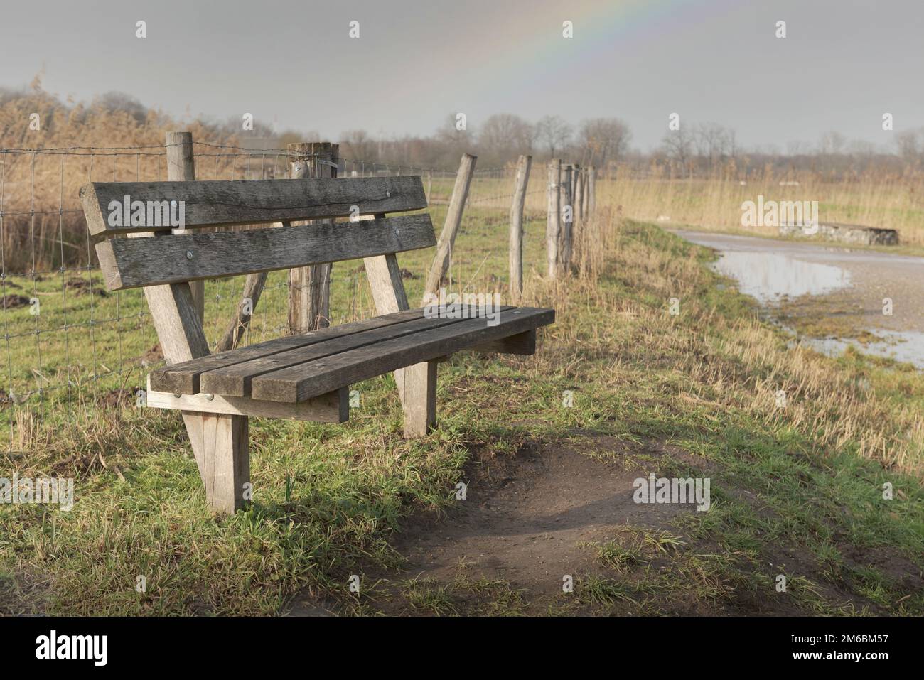 Bank im Herbstpark nach Regen mit Regenbogen Stockfoto