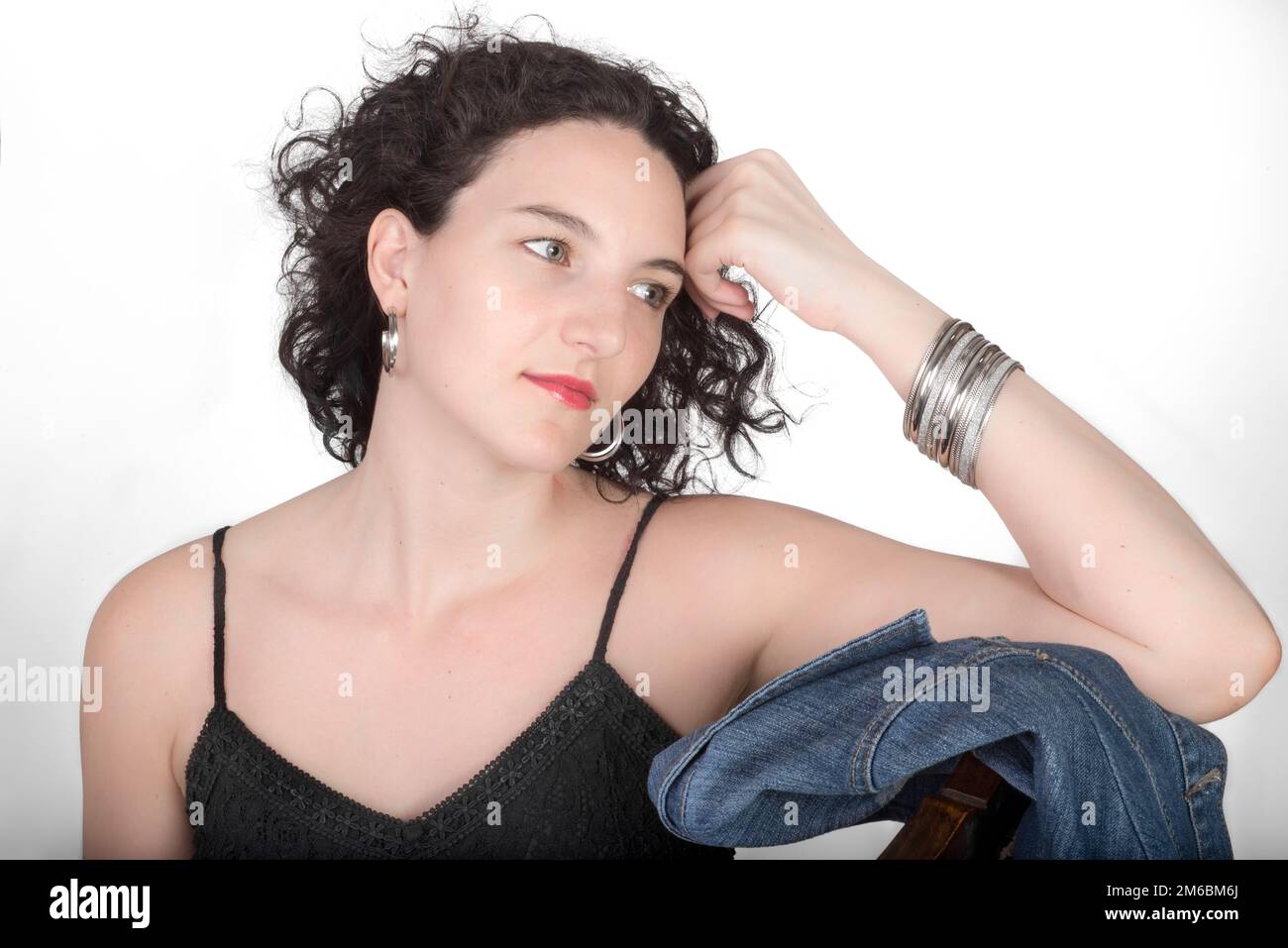 Junge Modell in ihrer Mitte der 20er Jahre saß auf einem holzstuhl mit einer blauen Jeans Jacke. Stockfoto