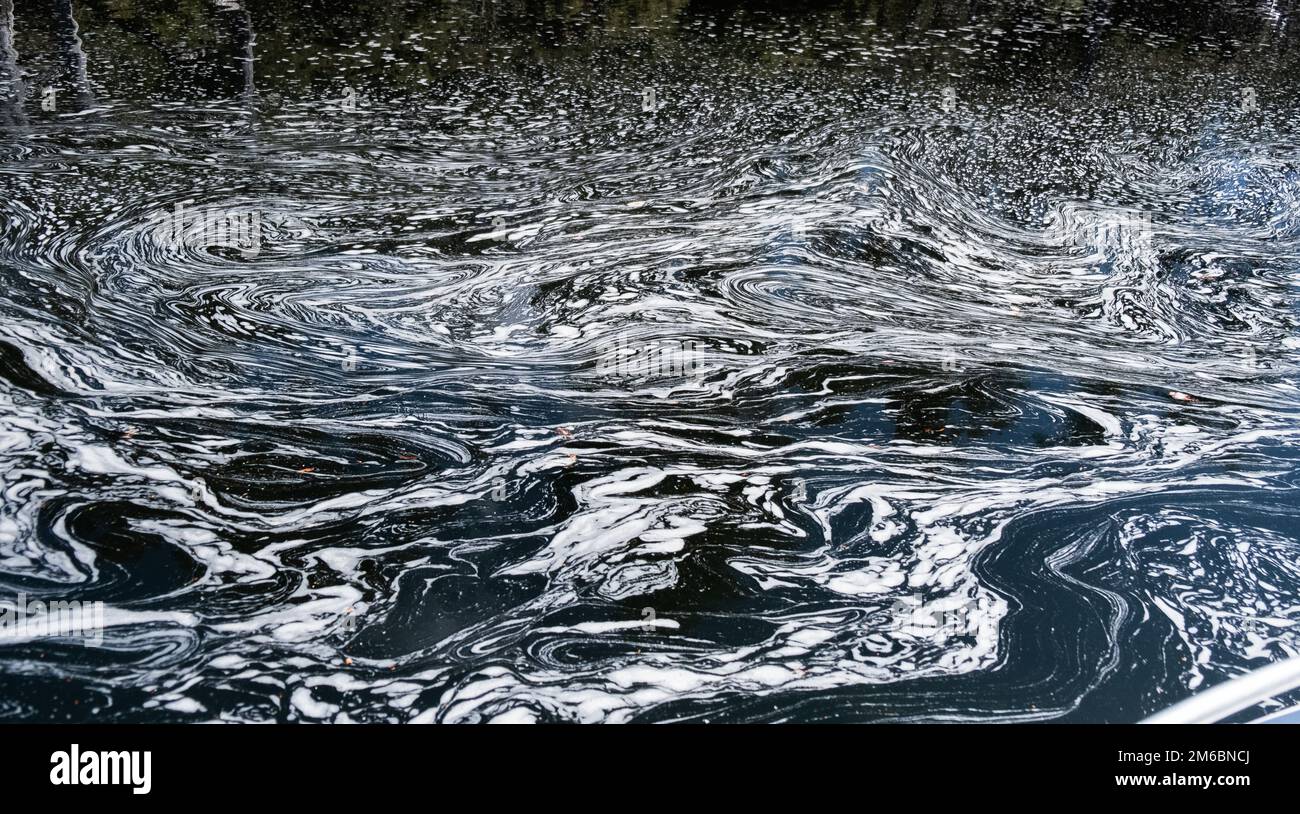 Schaum- und Blasenlinien drehen sich, um ein wunderschönes Muster zu erzeugen, wo sich zwei Flüsse treffen. Stockfoto