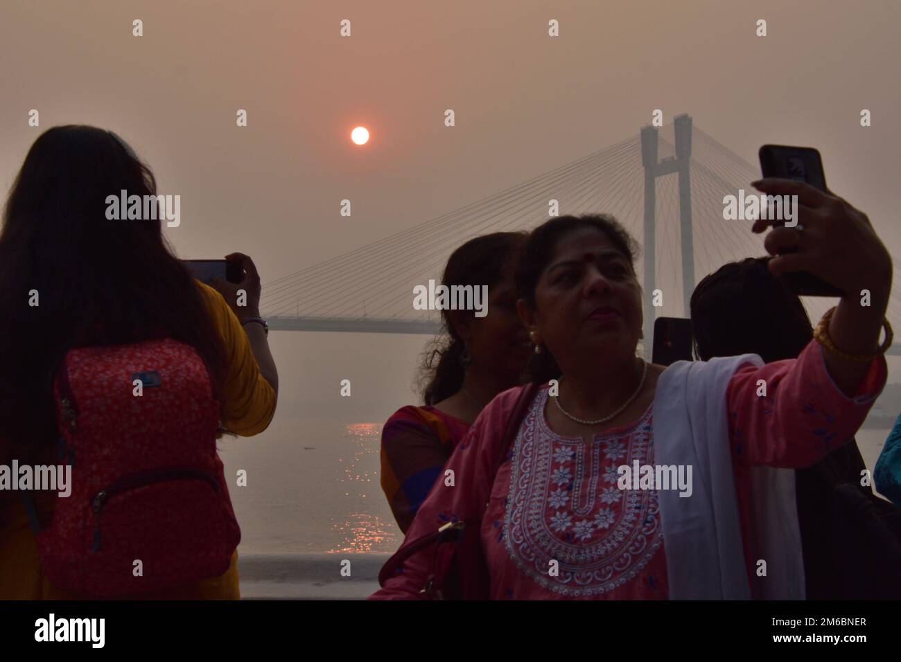 31. Dezember 2022, Kalkutta, Indien. Eine Person macht ein Selfie während des Sonnenuntergangs über die Howrah Bridge (Vidyasagar Setu) auf dem Fluss Ganges. Malerische Schönheit der untergehenden Sonne am letzten Tag des gregorianischen Kalenderjahres 2022, am 31. Dezember 2022, in Kalkutta, Indien. (Kreditbild: © Biswarup Ganguly/Eyepix via ZUMA Press Wire) Stockfoto