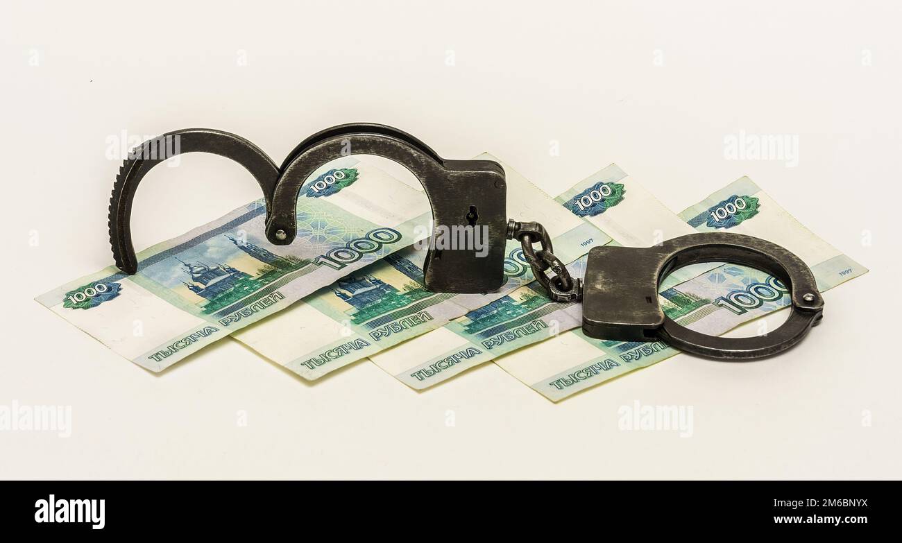 Eisenmetall-Handschellen und Banknoten 1000 russische Rubel auf weißem Hintergrund Stockfoto