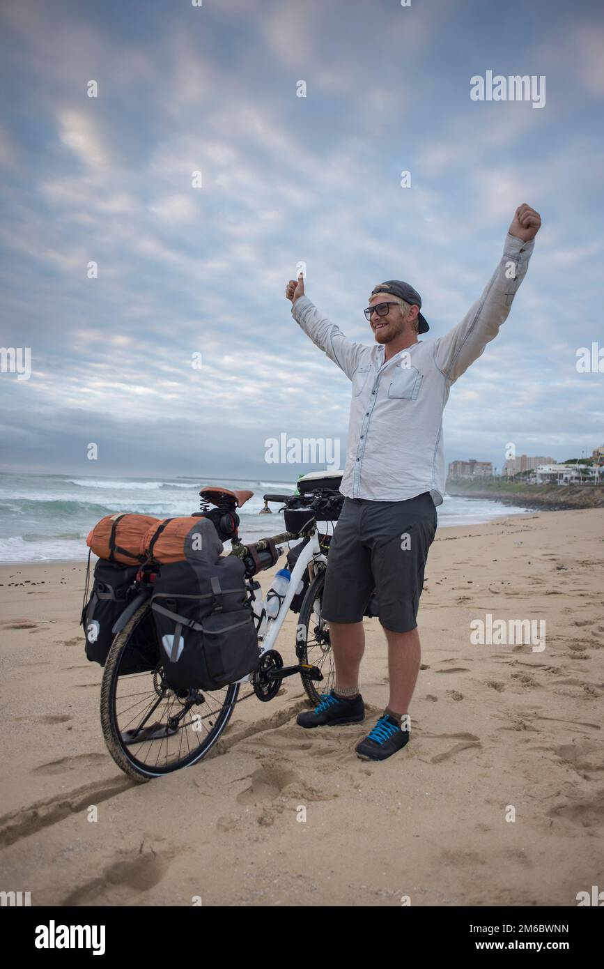 Langstreckenradfahrer am Strand mit Arms in the Air Stockfoto