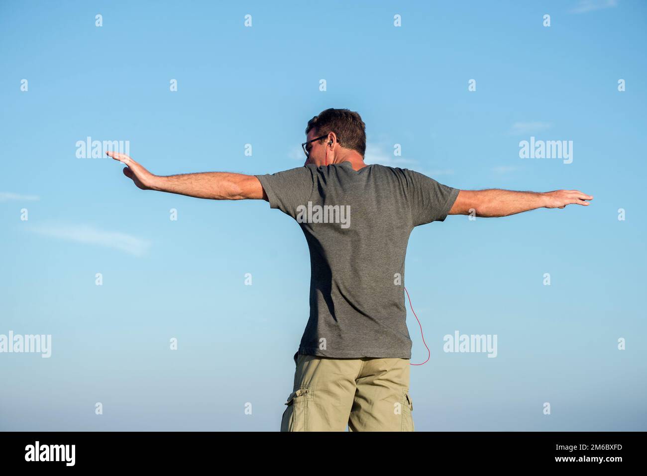 Der Mann, der von hinten gesehen wird, streckt die Arme Stockfoto