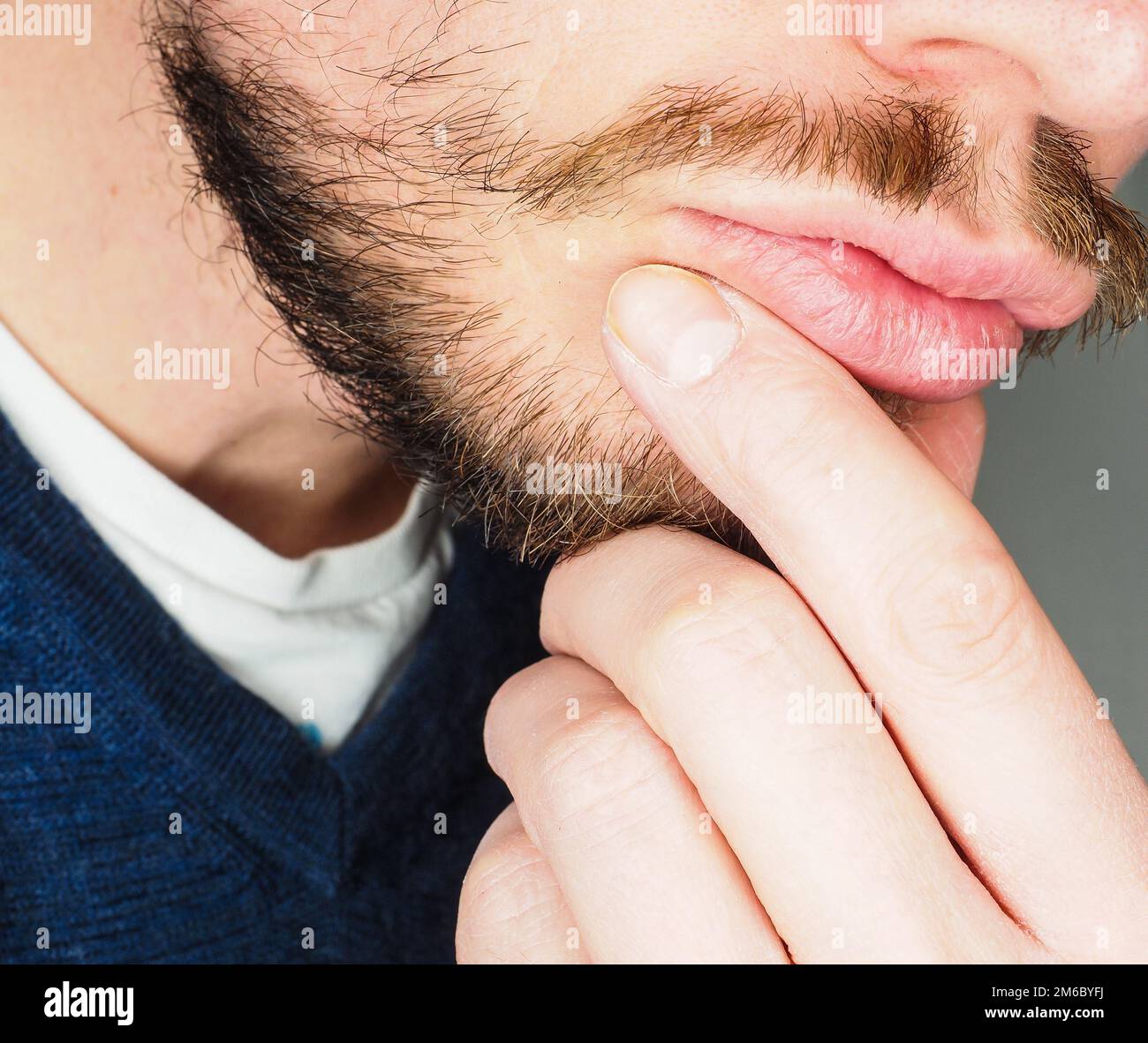 Männliche Person, in der Nahaufnahme mit Fingern in Bart hervorstehenden Lippen Stockfoto