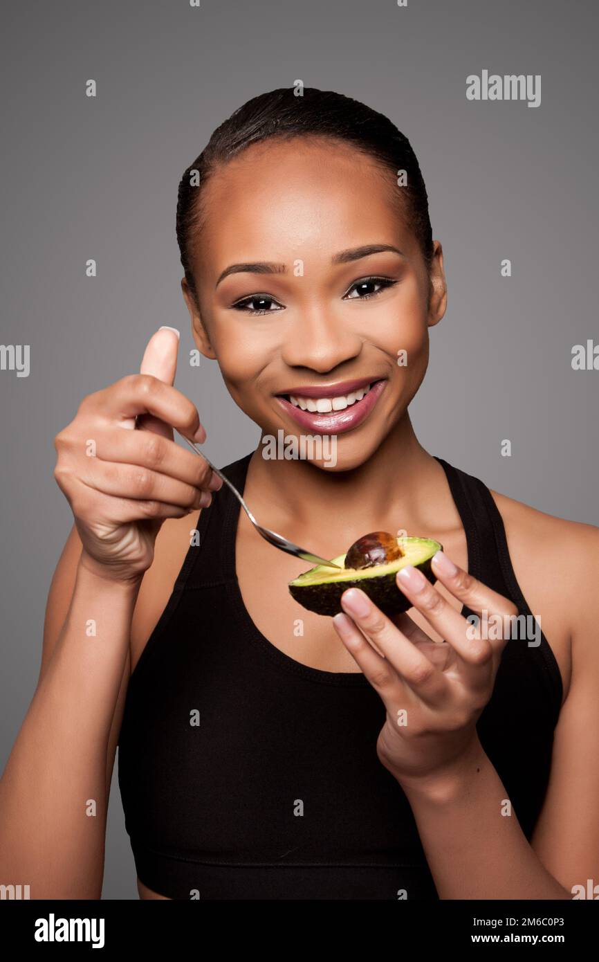 Glücklich gesund Schwarz asiatische Frau essen Avocado Stockfoto
